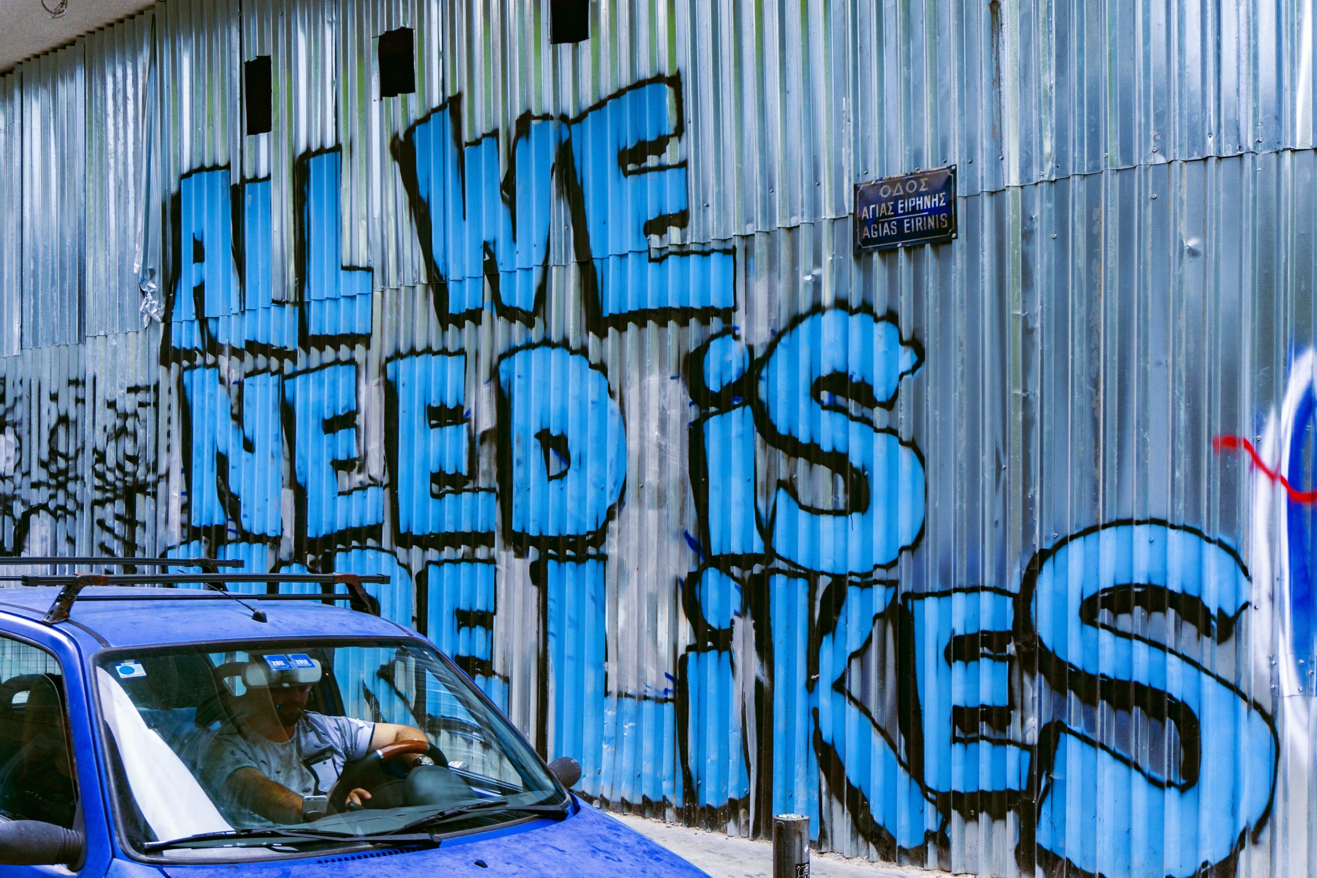 Ein Auto vor einer Wand auf der in Graffiti steht "All we need is likes"